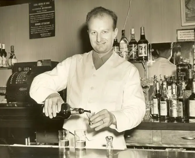 A man in white shirt standing at bar.