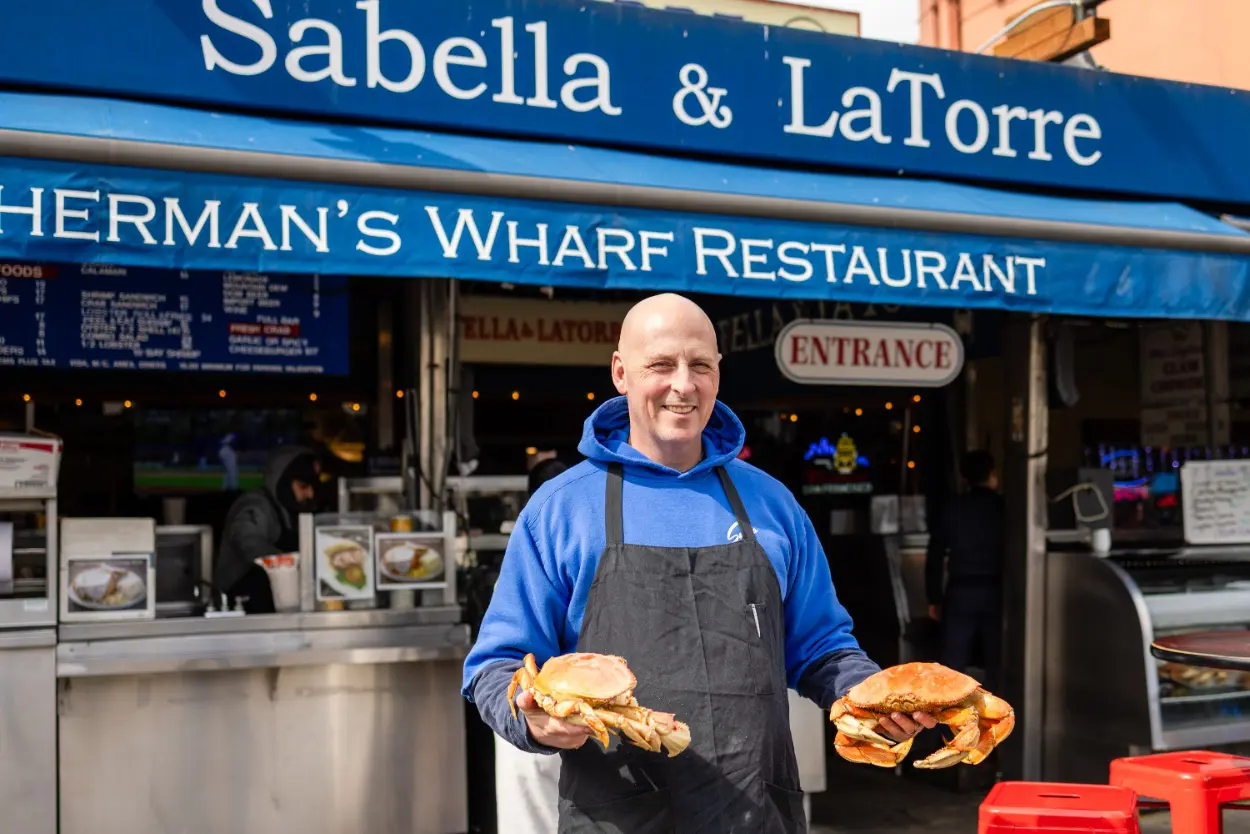 A man holding two sandwiches in front of a restaurant.
