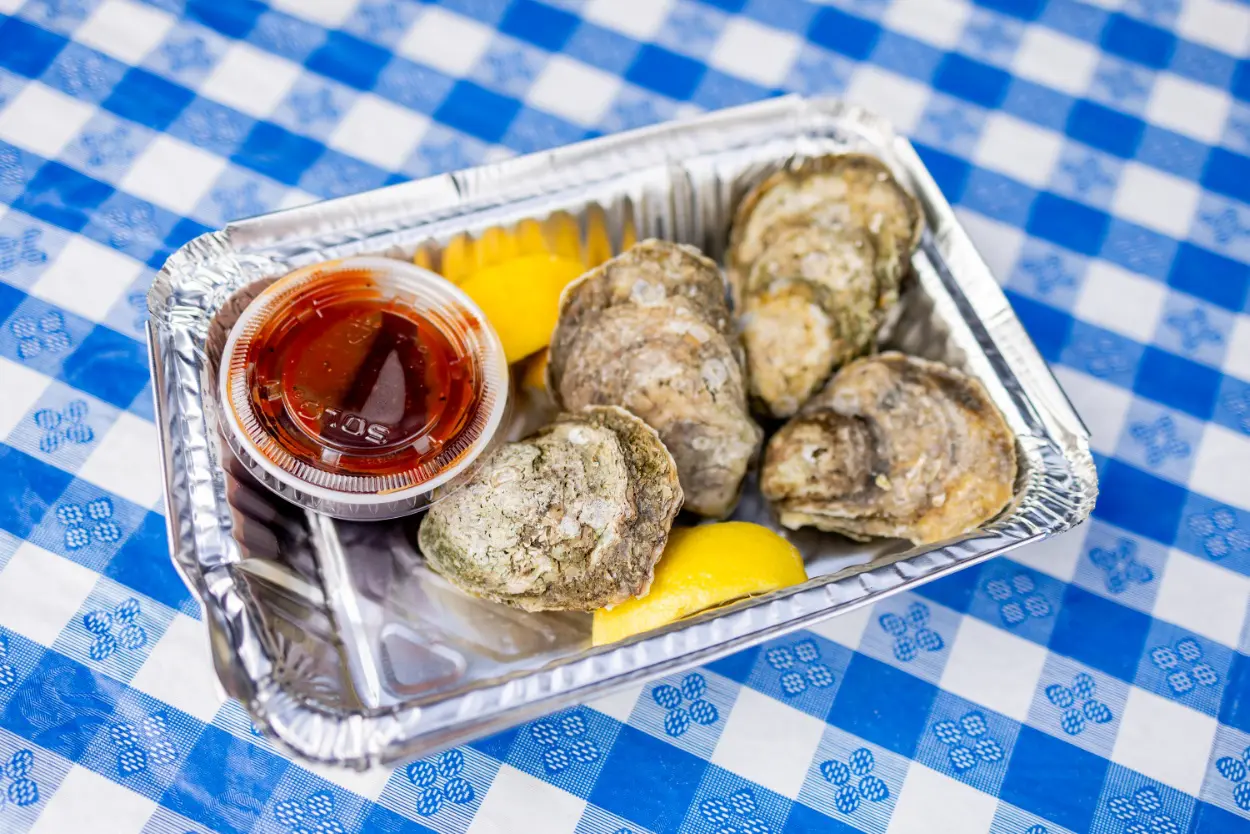 A tray of oysters and lemons on a table.