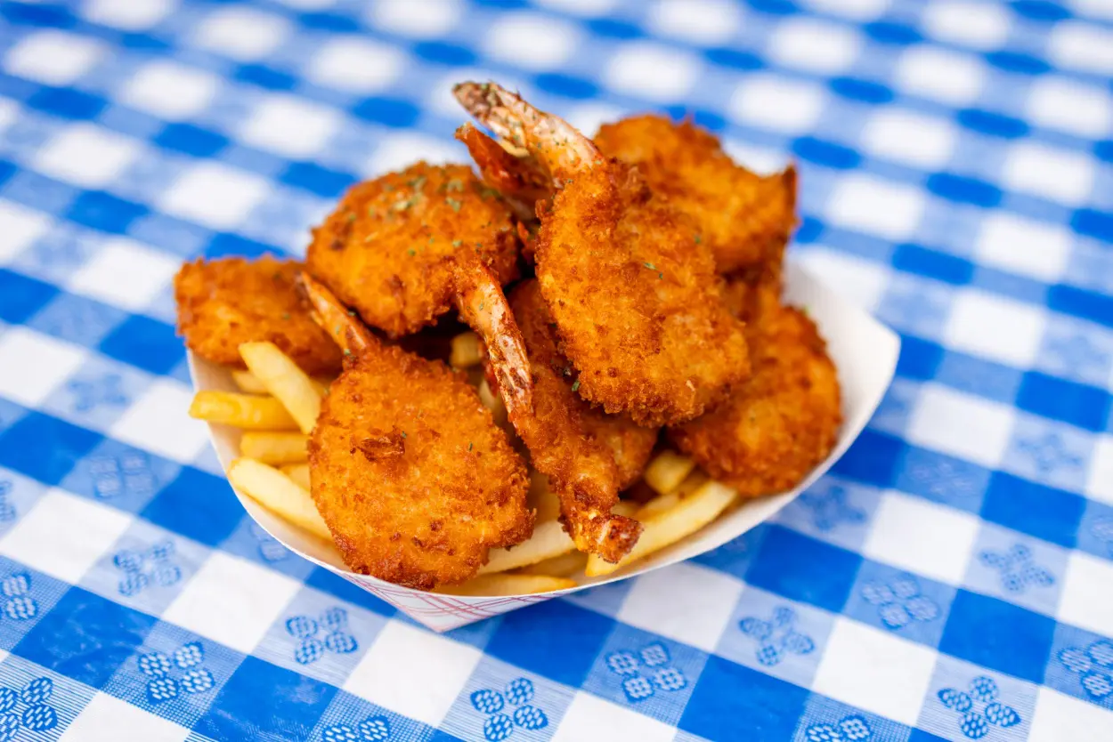 A plate of fried shrimp and french fries on a checkered tablecloth.