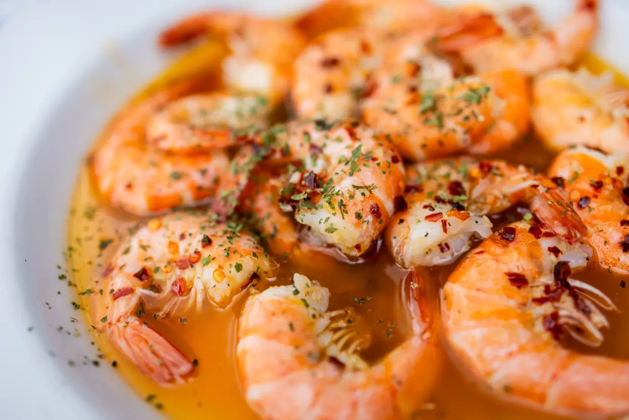 A plate of shrimp covered in sauce and spices.