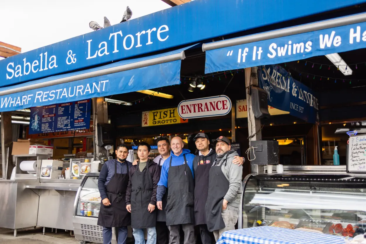 A group of people standing in front of a restaurant.