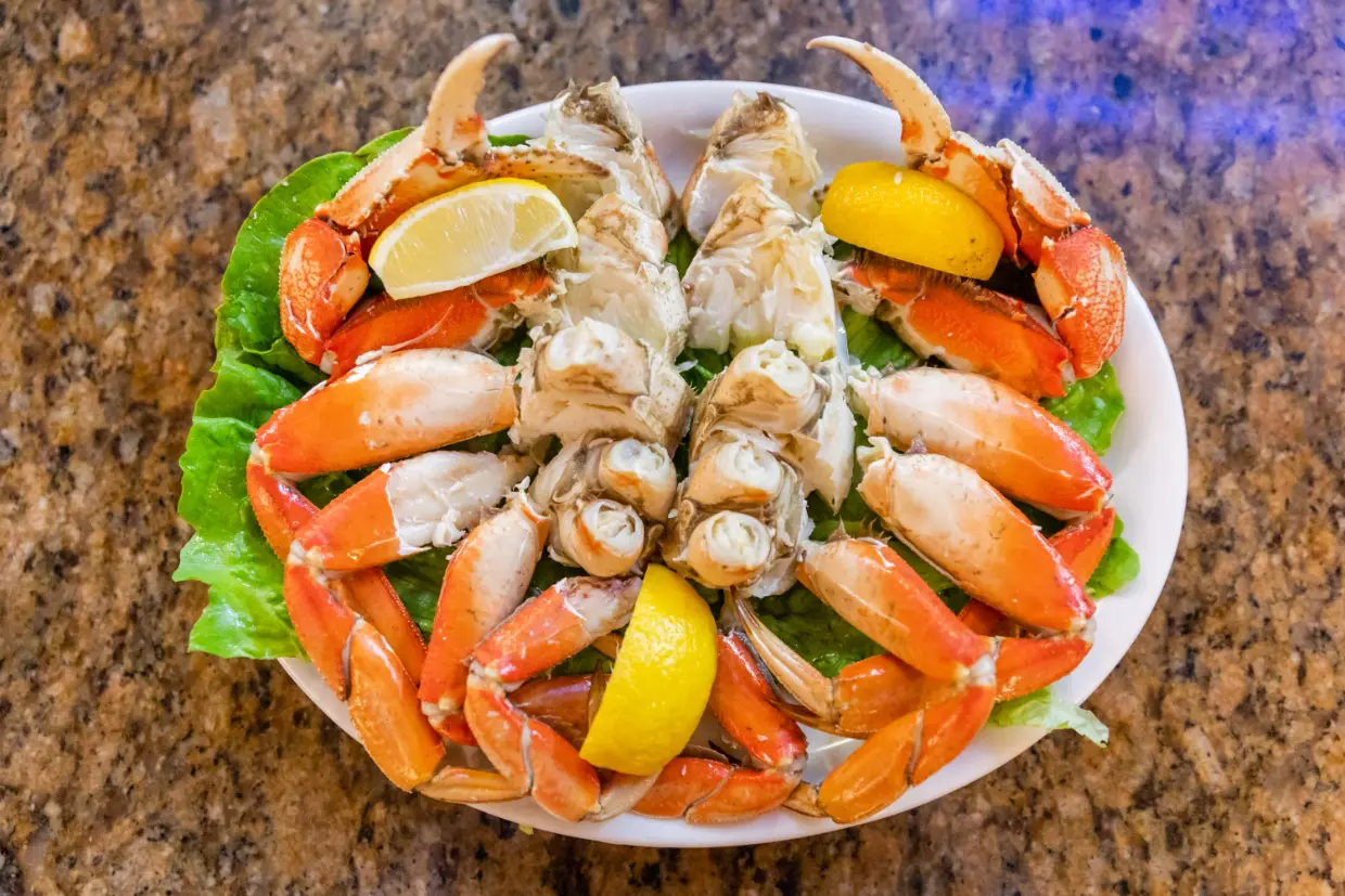 A plate of crab legs and lemons on the table.